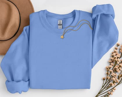 Gildan 18000 Sweatshirt — Folded with Props mockup in Carolina Blue
