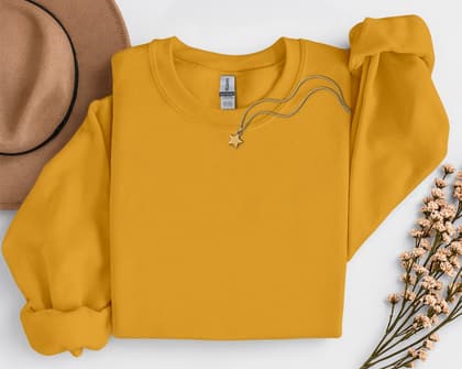 Gildan 18000 Sweatshirt — Folded with Props mockup in Gold